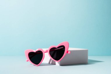 Güneşli gölgeli beyaz kürsüde güneş gözlüğü. Komik bir konsept..