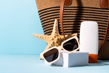 Yaz tatili konsepti. Güneş gözlüğü, güneş kremi ve mavi üzerinde güneşli gölgeler olan deniz kabuğu.