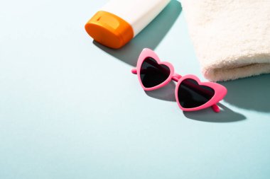 Yaz tatili konsepti. Güneş gözlüğü, güneş kremi ve güneşli gölgeli deniz kabuğu.
