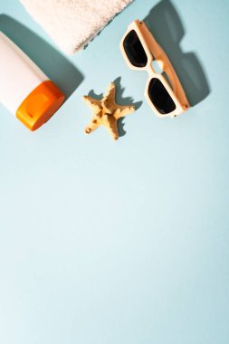 Yaz tatili konsepti. Güneş gözlüğü, güneş kremi ve güneşli gölgeli deniz kabuğu.