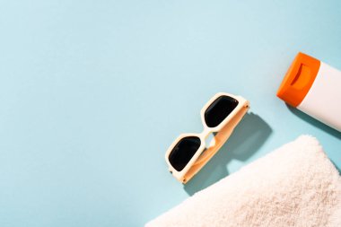 Yaz tatili konsepti. Güneş gözlüğü, güneş kremi ve güneşli gölgeli deniz kabuğu.