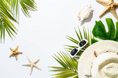 Beyaz arka planda yaz aksesuarları palmiye yaprakları, şapka, güneş gözlükleri, deniz kabukları. Moda gölgeleri. Yaz tatili, yaz tatili konsepti.