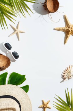 Beyaz arka planda yaz aksesuarları palmiye yaprakları, şapka, güneş gözlükleri, deniz kabukları ve hindistan cevizi. Moda gölgeleri. Yaz tatili, yaz tatili.