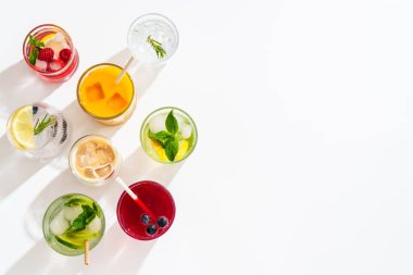 Beyaz arka planda buzlu içecekler. Limonata, mojito, ahududu limonatası, taze meyveli tonik suyu. Metin için boşluk olan üst görünüm.