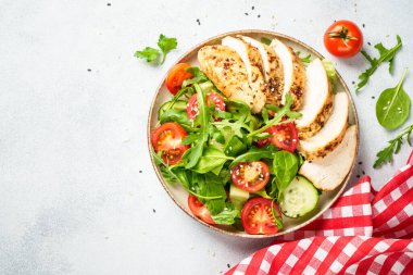 Izgara tavuk göğsü ve beyaz mutfak masasında taze sebzeli tavuk salatası. Üst görünüm.