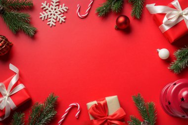 Kırmızı arka planda Noel yatıyordu. Noel süslemeleri ve hediyeleriyle Noel kompozisyonu.