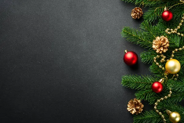 Noel arkaplanı köknar ağacı ve siyah üzerine renkli tatil süslemeleri ile yatıyordu..