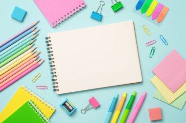 Not defteri, kalemler, kalemler ve diğer malzemeler. Düz resim mavi arkaplanda yatıyordu.