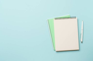 Mavi arka planda not defteri ve kalem. Kopyalama alanı olan düz.