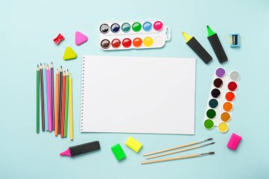 Çizim defteri, kalemler, suluboya boyalar ve mavi arka planda kalemler. Metin için alanı olan sanat yaratıcı bileşimi.