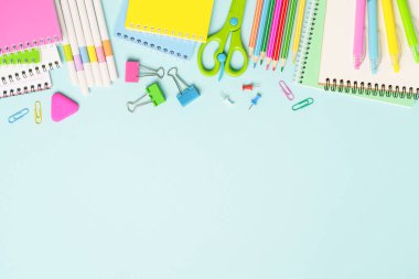 Okul gereçleri ya da mavi arka planda ofis kağıtları. Not defteri, kalemler, kalemler ve diğerleri. Metin için boşluk olan üst görünüm.