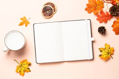 Sonbahar çalışma alanı. Not defteri, bir fincan kahve ve sarı yapraklar. Metin için boşluk ile düz uzandı.