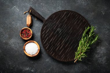 Baharat ve bitkiler, siyah arka planda kesim tahtası. Metin için boşluk ile düz uzandı.