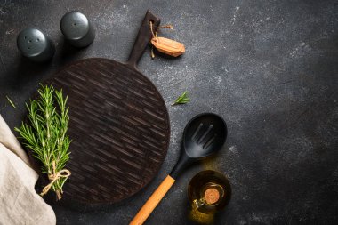 Mutfak masası. Baharat ve bitkiler, siyah arka planda kesim tahtası. Kopyalama alanı olan üst görünüm.