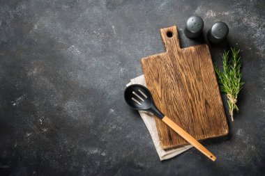 Siyah arka planda çatal bıçak ve otlarla kesme tahtası. Kopyalama alanı olan üst görünüm.