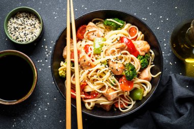 Siyah arka planda tavuk ve sebzeli Asya eriştesi. Geleneksel Asya mutfağı.