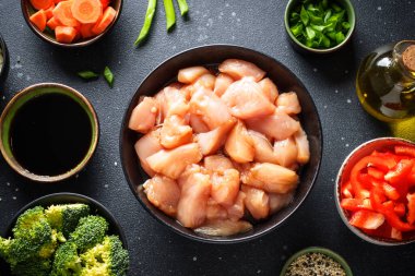 Asya yemekleri hazırlığı. Soya soslu tavuk, kırmızı biber, brokoli ve siyah arka planda soğan. Çiğ yemek, tarifler için malzemeler..