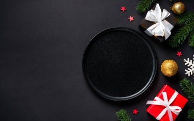 Noel yemeği. Siyah tabak, şarap kadehi, çatal bıçak takımı ve bayram süslemeleriyle Noel sofrası. Metin için boşluk ile düz uzandı.