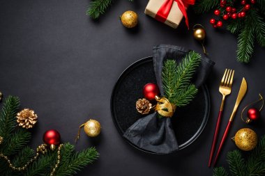 Noel yemeği. Siyah tabak, şarap kadehi, çatal bıçak takımı ve bayram süslemeleriyle Noel sofrası. Metin için boşluk ile düz uzandı.