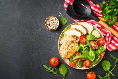 Siyah masada ızgara tavuk eti ve yeşil salata. Tasarım için alanı olan üst görünüm.
