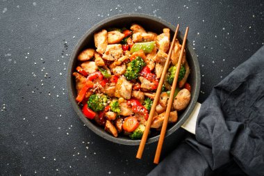 Sebzeli tavuk kızartması ve siyah arka planda susam. Geleneksel Asya mutfağı.