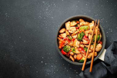 Sebzeli tavuk kızartması ve siyah arka planda susam. Geleneksel Asya mutfağı.