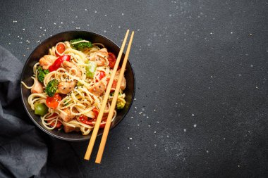 Siyah arka planda tavuk ve sebzeli Asya eriştesi. Tasarım için alanı olan üst görünüm.