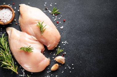 Tavuk göğsü, siyah masada baharatlı çiğ tavuk eti. Üst görünüm.
