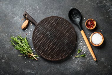 Kesme tahtası, baharatlar ve siyah arka planda bitkiler. Metin için boşluk ile düz uzandı.