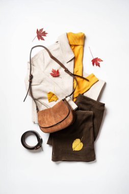 Sonbahar kumaşı ve aksesuarları beyaz arka planda. Atkı, sarı kazak ve çanta. Kopyalama alanı olan düz.