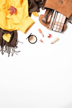 Sonbahar düz arka plan yatıyordu. Sıcak bez, poşet ve kozmetik ürünleri. Düşmüş yapraklı kadın bezi ve güzellik ürünleri..