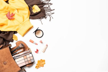 Sonbahar düz arka plan yatıyordu. Sıcak bez, poşet ve kozmetik ürünleri. Düşmüş yapraklı kadın bezi ve güzellik ürünleri..