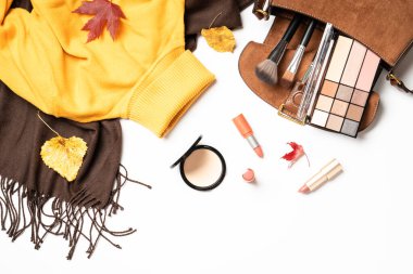 Sonbahar kumaşı ve aksesuarları beyaz arka planda. Atkı, kazak, çanta ve yapraklı kozmetik ürünler. Dizayn için alanı olan düz uzandı.
