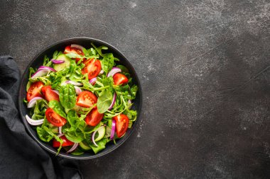 Yapraklı ve sebzeli taze salata. Siyah üzerine üst görünüm.