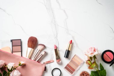 Beyaz arka planda gül çiçekli makyaj ürünleri olan kozmetik çanta. Kopyalama alanı olan düz.