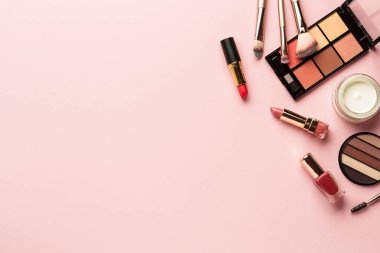 Makyaj ürünleri pembeye yatar. Göz farı, fosforlu kalem, krem, ruj ve kozmetik fırçalar..