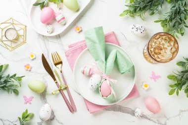 Paskalya yemeği geçmişi, beyaz arka planda tatil masası ayarı. Beyaz tabak, çatal bıçak takımı ve paskalya süslemeleri..