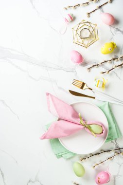 Beyaz arka planda süslemeleri olan Paskalya yemekleri. Beyaz tabak, çatal bıçak takımı ve komik paskalya süslemeleri..