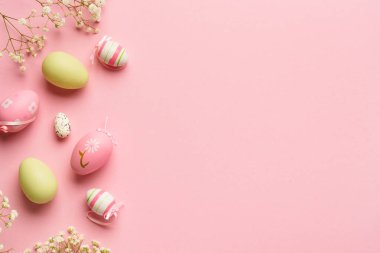 Pembe arka planda Paskalya yumurtaları. Renkli yumurtalar, çiçekler, tatil süslemeleri. Kopyalama alanı olan düz.