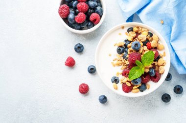 Beyaz masada taze böğürtlenli yoğurt ve tahıl gevreği. Sağlıklı atıştırmalıklar ya da kahvaltı. Beyaz arkaplanda kopyalama alanı olan üst görünüm.