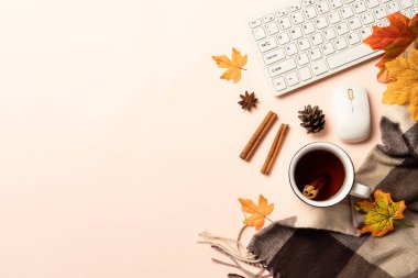Sonbahar ofis masası. Laptop, bir fincan çay, baharatlar ve dökülen yapraklı eşarp. Metin için boşluk ile düz uzandı.