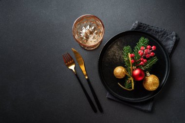 Noel sofrası. Noel yemeği. Siyah arka planda siyah tabaklar, çatal bıçak takımı ve süslemeler. Kopyalama alanı olan düz.