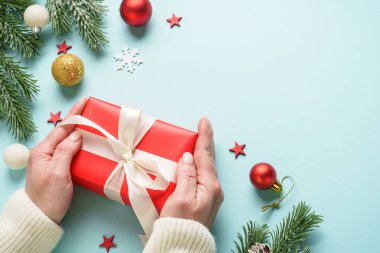 Hediye kutusunu maviye veriyorum. Noel tatiline kırmızı hediye veren bir kadın.