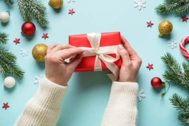 Hediye kutusunu maviye veriyorum. Noel tatiline kırmızı hediye veren bir kadın.