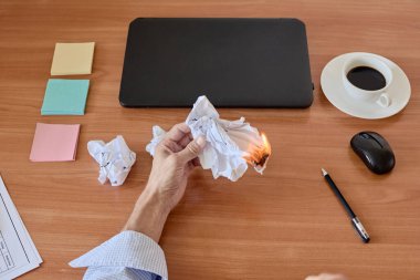 Ofis masasında buruşmuş kağıt parçaları yanıyor.
