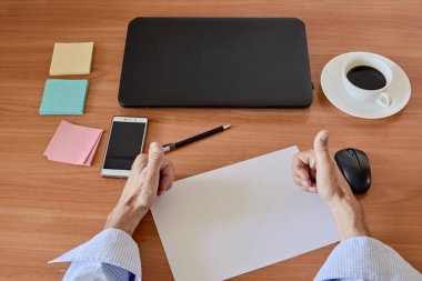 Male hands showing thumbs up on the background of working place