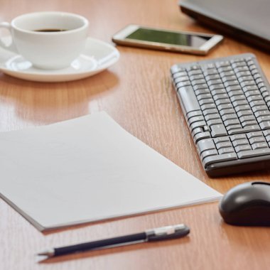 Office workplace on wooden table with keyboard and sheet of paper