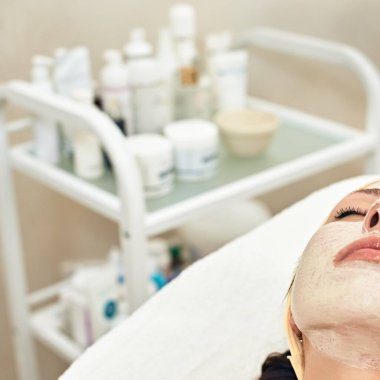 Portrait of attractive young woman lying in beauty salon with mask on her face