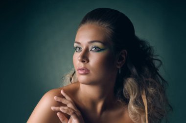 Stüdyonun arka planında çıplak omuzlarıyla poz veren güzel sarışın.