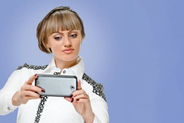 Mavi arka planda cihazı olan sarışın iş kadını portresi